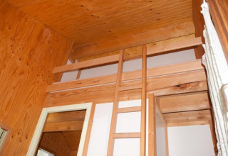 Vista interior de una cabaña de madera con altillo y escalera en Chalet Olga, Camping Seasonova Les Vosges du Nord.