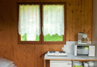 Interieur van Chalet Anaïs bij Camping Seasonova Les Vosges du Nord, Frankrijk, met kitchenette en raam.