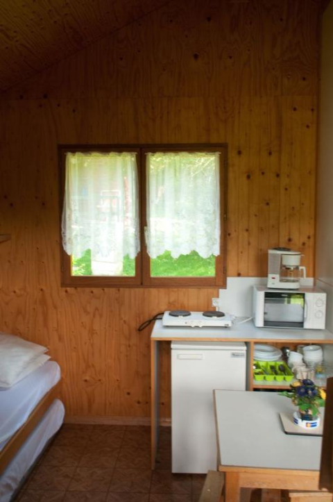 Interior of Chalet Anaïs at Camping Seasonova Les Vosges du Nord, France, featuring kitchenette and window.