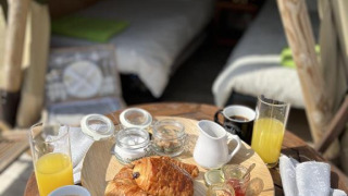 Petit-déjeuner avec croissants et jus devant un tipi au Camping Seasonova Les Vosges du Nord, France.