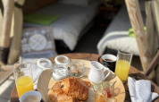 Desayuno con croissants y jugo frente a un tipi en Camping Seasonova Les Vosges du Nord, Francia.