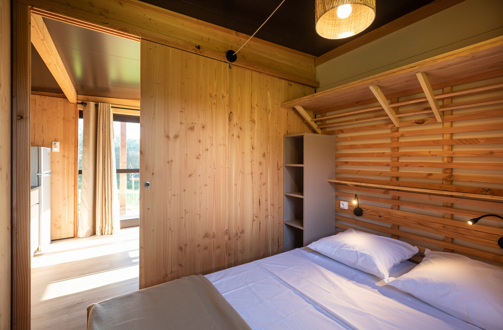 Slaapkamer in Chalet Evasion Vista bij Huttopia Les Falaises - Normandie, houten muren en tweepersoonsbed.