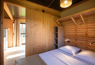 Slaapkamer in Chalet Evasion Vista bij Huttopia Les Falaises - Normandie, houten muren en tweepersoonsbed.