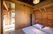 Dormitorio del Chalet Evasion Vista en Huttopia Les Falaises - Normandie, paredes de madera y cama doble.
