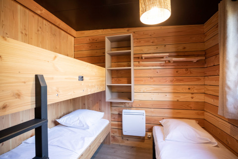 Houten slaapkamer met stapelbed en eenpersoonsbed in Chalet Evasion Vista bij Huttopia Les Falaises - Normandie.