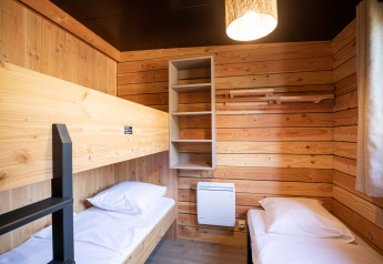Schlafzimmer mit Holzverkleidung, Etagenbett, Einzelbett im Chalet Evasion Vista bei Huttopia Les Falaises - Normandie.
