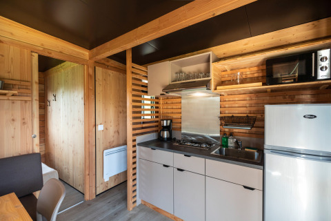 Moderne chaletkeuken met houten panelen, fornuis, koelkast en magnetron in Chalet Evasion Vista, Normandië.