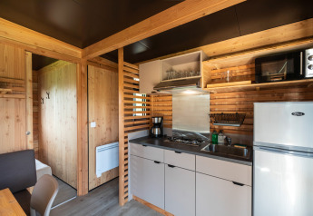 Moderne chalétkøkken med træpaneler, gaskomfur, mikroovn og køleskab i Chalet Evasion Vista, Normandiet.