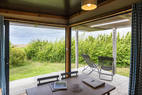 Uitzicht vanuit Chalet Evasion Vista bij Huttopia Les Falaises - Normandie op terras en groene omgeving buiten.
