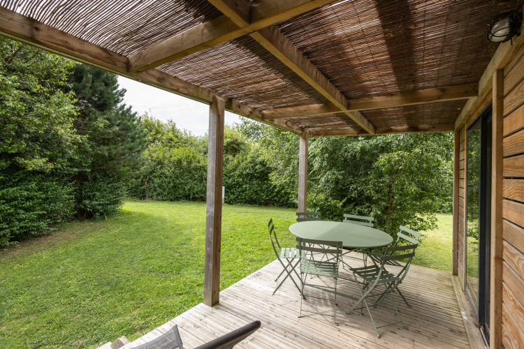 Terrasse du Chalet Ottawa à Huttopia Les Falaises - Normandie, France, avec table verte, chaises et jardin.