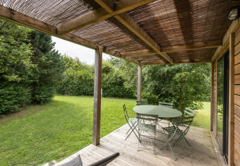 Terrasse du Chalet Ottawa à Huttopia Les Falaises - Normandie, France, avec table verte, chaises et jardin.