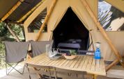 Tienda de safari Tente Canadienne en Huttopia Les Falaises - Normandie con mesa, sillas y equipamiento de camping.