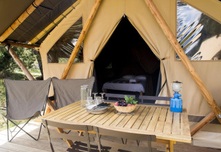 Tienda de safari Tente Canadienne en Huttopia Les Falaises - Normandie con mesa, sillas y equipamiento de camping.