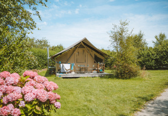 Safari-tent Tente Trappeur bij Huttopia Les Falaises - Normandië, omgeven door bloemen en groene weide.