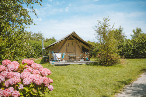 Safari-Zelt Tente Trappeur bei Huttopia Les Falaises in der Normandie, umgeben von Blumen und Grünfläche.