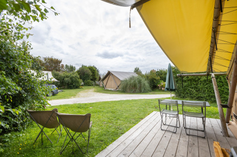 Zicht vanaf een houten terras bij de safaritent Tente Trappeur op Huttopia Les Falaises, Normandië, Frankrijk.