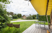Zicht vanaf een houten terras bij de safaritent Tente Trappeur op Huttopia Les Falaises, Normandië, Frankrijk.