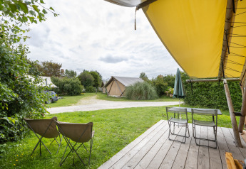 Zicht vanaf een houten terras bij de safaritent Tente Trappeur op Huttopia Les Falaises, Normandië, Frankrijk.