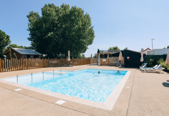 Outdoor swimming pool with sun loungers and umbrellas at Camping Seasonova Ile de Ré, Nouvelle-Aquitaine, France.