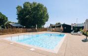Outdoor swimming pool with sun loungers and umbrellas at Camping Seasonova Ile de Ré, Nouvelle-Aquitaine, France.