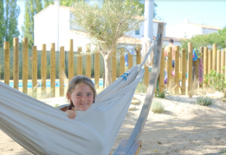 Een kind ontspant in een hangmat bij Camping Seasonova Ile de Ré, een vakantiepark in Nouvelle-Aquitaine, Frankrijk.