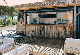 Buitencafé met houten zitjes en bamboe bar bij Camping Seasonova Ile de Ré in Nouvelle-Aquitaine, Frankrijk.