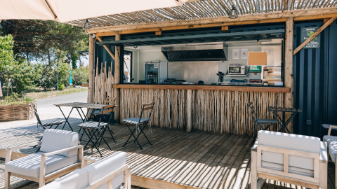 Udendørs caféområde med træmøbler og bambusbar på Camping Seasonova Ile de Ré i Nouvelle-Aquitaine, Frankrig.