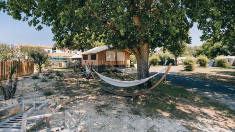 Camping Seasonova Ile de Ré : tentes, hamacs et arbres dans un parc de vacances ensoleillé en Nouvelle-Aquitaine, France.