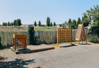 Outdoor games area featuring wooden games in a scenic rural setting at Camping Seasonova Ile de Ré, France.