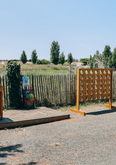 Outdoor-Spielbereich mit Holzspielen und ländlicher Kulisse bei Camping Seasonova Ile de Ré, Frankreich.