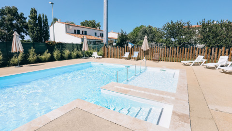 Piscina al aire libre con tumbonas y sombrillas en Camping Seasonova Ile de Ré, Nueva Aquitania, Francia.