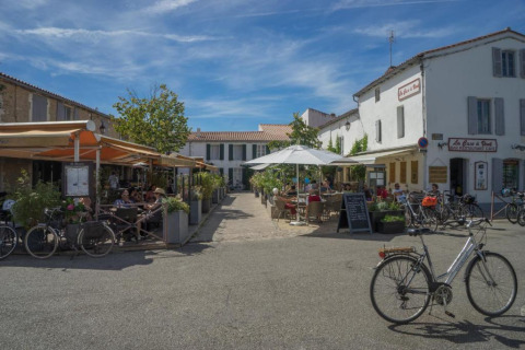 Cafés al aire libre y bicicletas bajo un cielo azul en Camping Seasonova Ile de Ré, Nouvelle-Aquitania, Francia.