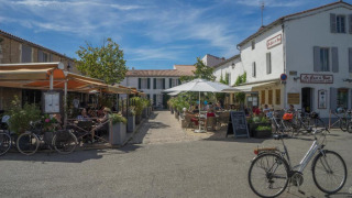 Gemütliche Straßencafés und Fahrräder unter blauem Himmel bei Camping Seasonova Ile de Ré in Frankreich.