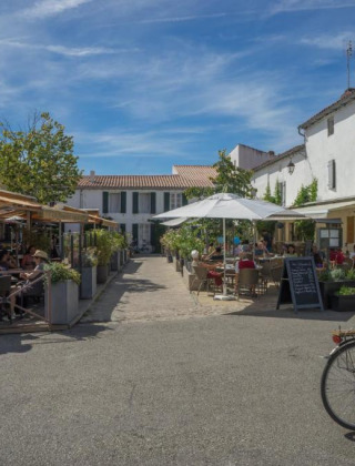 Cafés al aire libre y bicicletas bajo un cielo azul en Camping Seasonova Ile de Ré, Nouvelle-Aquitania, Francia.