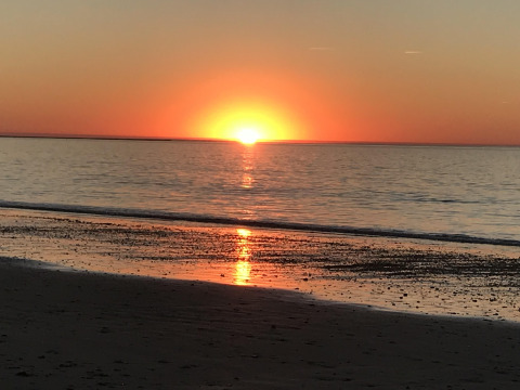 Zonsondergang aan zee nabij Les Portes-en-Ré, Frankrijk, met een oranje horizon en kalme zee.
