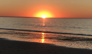 Sonnenuntergang am Meer bei Les Portes-en-Ré, Frankreich, mit orangefarbenem Himmel und sanften Wellen.