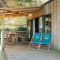 Sfeervol Cottage Prestique met houten terras, twee blauwe stoelen en overdekte buitenzitruimte.