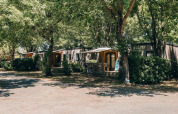 Cottage Prestige op Camping Seasonova Ile de Ré, Frankrijk, genesteld tussen groene bomen en struiken.
