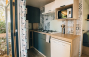 Cocina moderna en una cabaña Cottage Prestique en Camping Seasonova Ile de Ré, Francia, con electrodomésticos.