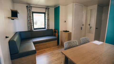 Vista interior de Cottage Prestique en Camping Seasonova Ile de Ré, Francia, con sofá moderno y mesa de comedor.