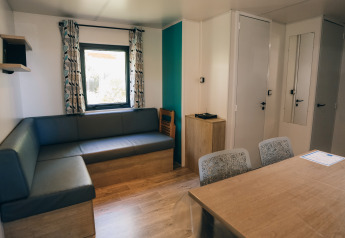 Vista interior de Cottage Prestique en Camping Seasonova Ile de Ré, Francia, con sofá moderno y mesa de comedor.