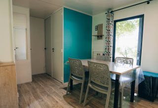 Eetruimte in Cottage Prestique, Camping Seasonova Ile de Ré, Frankrijk, met vier stoelen en een moderne stijl.