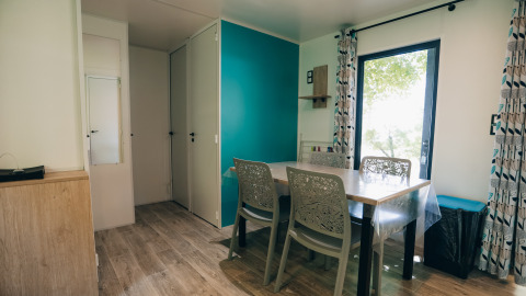 Essbereich im Cottage Prestique, Camping Seasonova Ile de Ré, Frankreich, mit vier Stühlen und Holzboden.