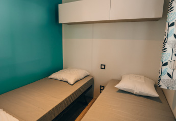 Twee eenpersoonsbedden in een lichte, moderne kamer van Cottage Prestique, Camping Seasonova Ile de Ré.