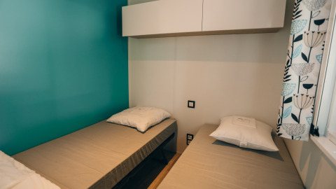 Dos camas individuales en una habitación luminosa y moderna en Cottage Prestique, Camping Seasonova Ile de Ré, Francia.