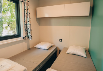 Et værelse i Cottage Prestique på Camping Seasonova Ile de Ré i Frankrig med to enkeltsenge og vindue.
