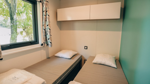 Habitación en Cottage Prestique de Camping Seasonova Ile de Ré, Francia, con dos camas individuales y ventana.