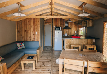 Interno della Lodge Premium al Camping Seasonova Ile de Ré, Francia, con arredi in legno e servizi moderni.