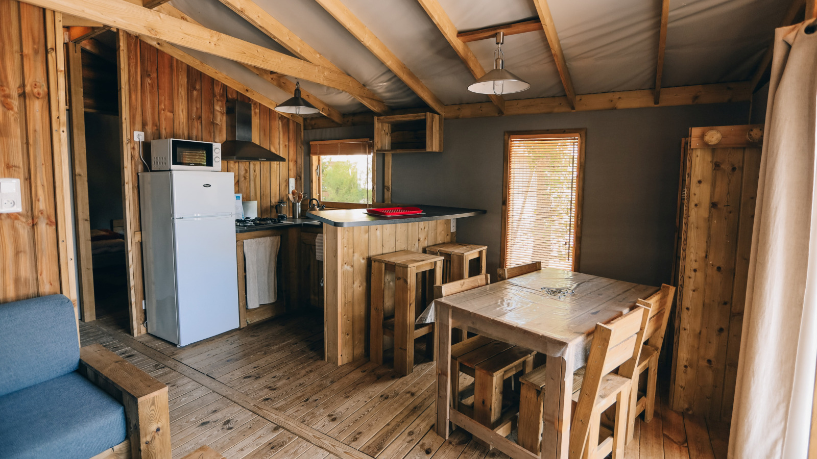 Binnenaanzicht van de Lodge Premium cabin op Camping Seasonova Ile de Ré met houten meubels en keuken.