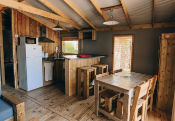 Vista interna della Lodge Premium al Camping Seasonova Ile de Ré con mobili in legno e area cucina.